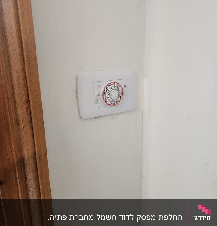 טיימר מכני על קיר לבן ליד דלת עץ